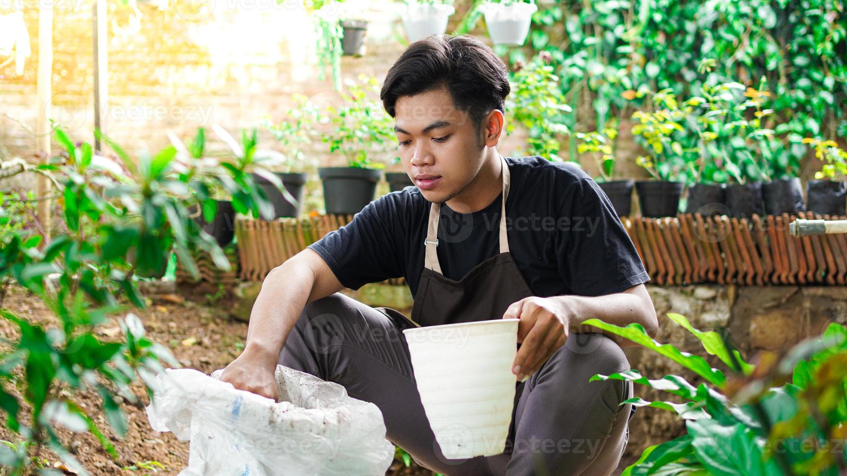 hombre asiático prepara un lugar para plantar con maceta y tierra foto