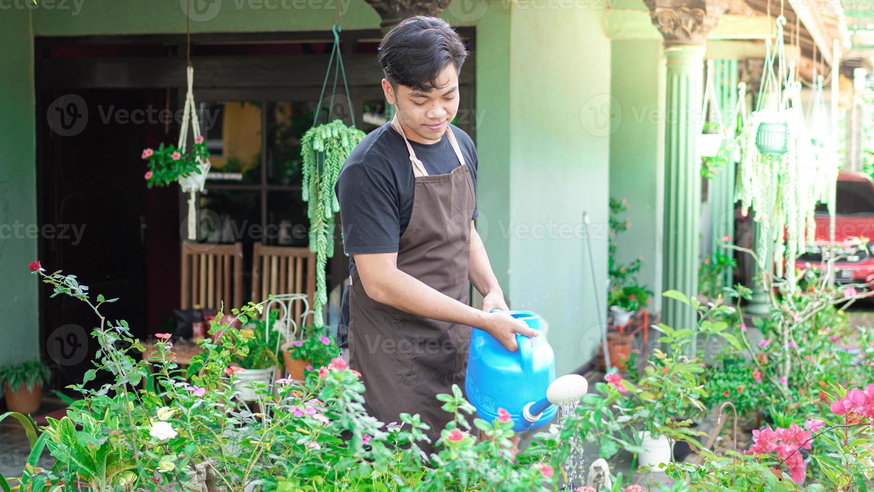 Asian man taking care watering flower at home garden photo