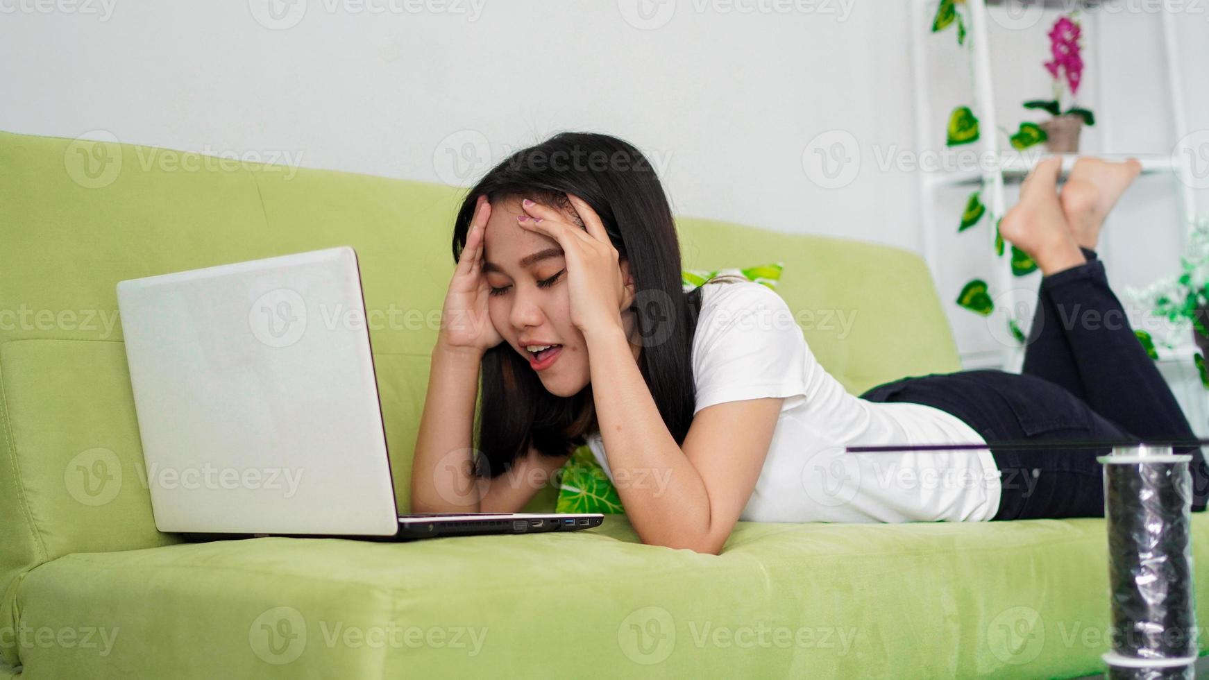 mujeres asiáticas sentadas en una silla trabajando desde casa en una laptop y pensando en la solución del problema foto