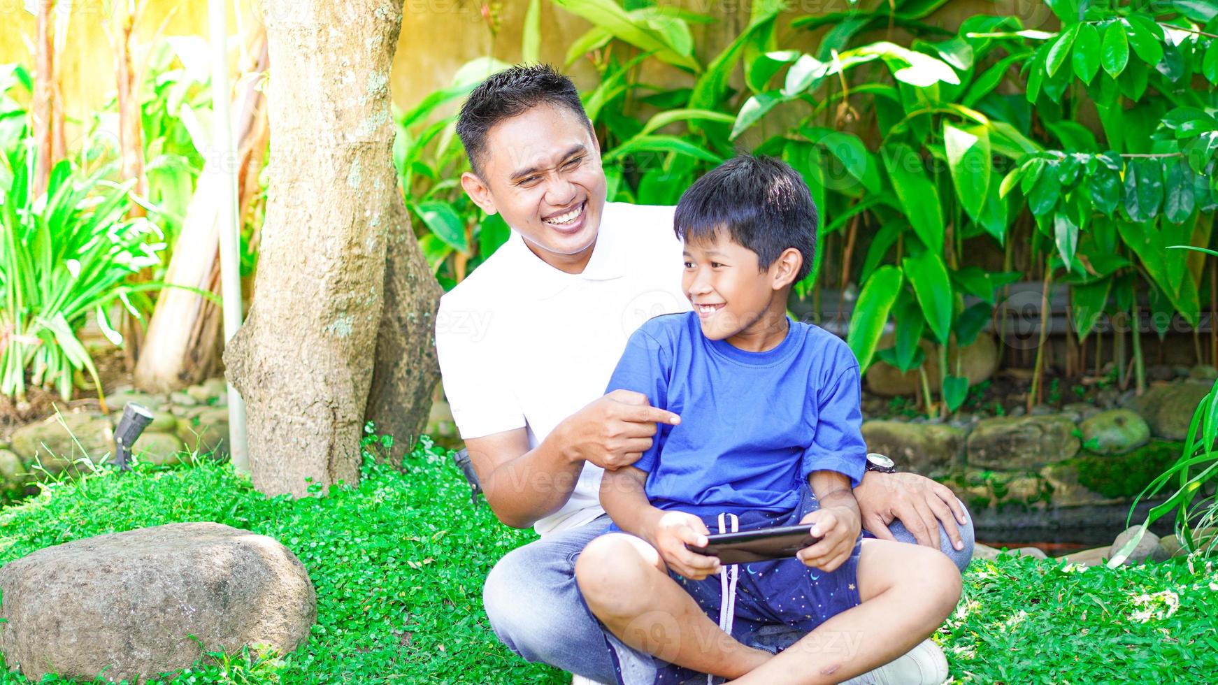 dad and son play games mobile in the park photo