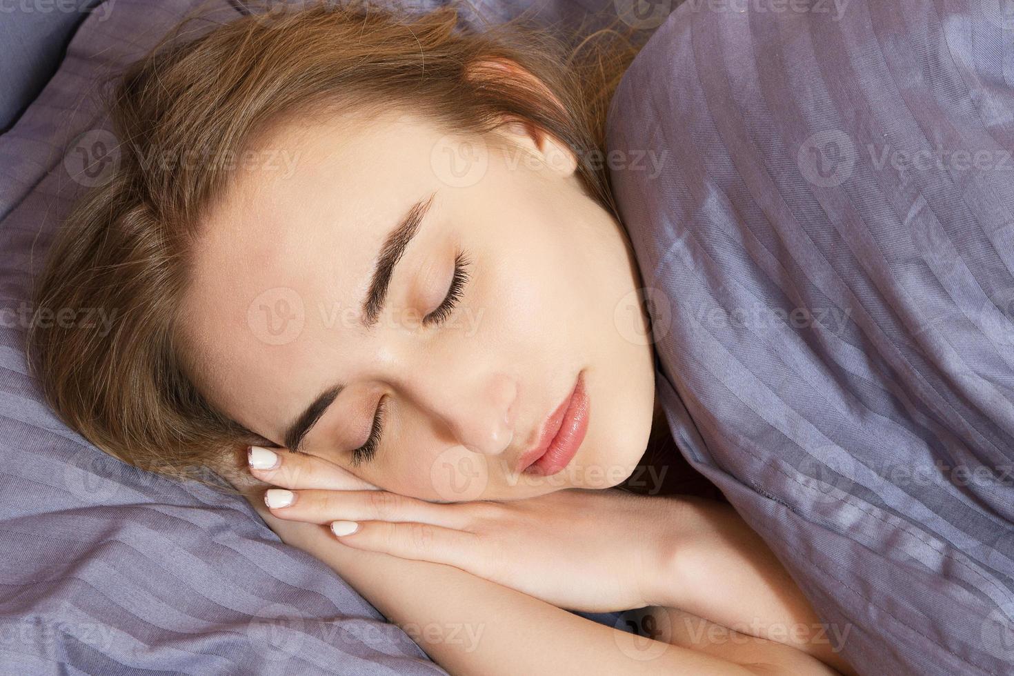 la mujer duerme en la cama por la noche, el sueño saludable, la niña duerme en el dormitorio. foto