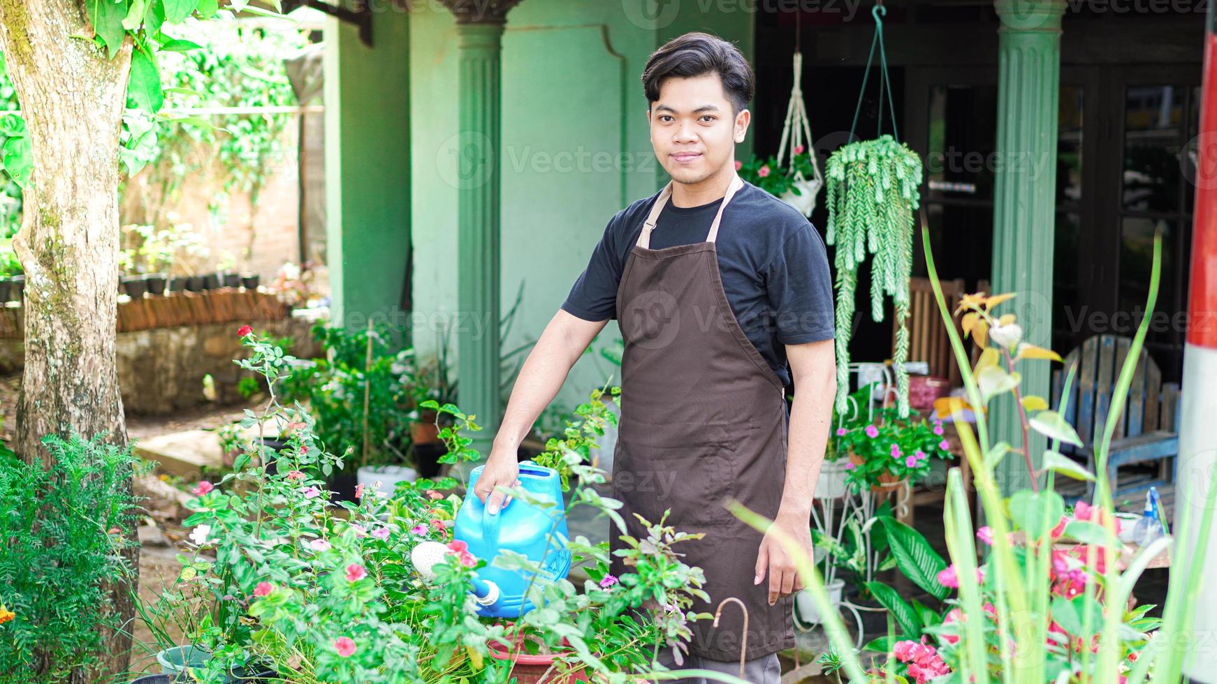 Asian man taking care watering flower at home garden photo