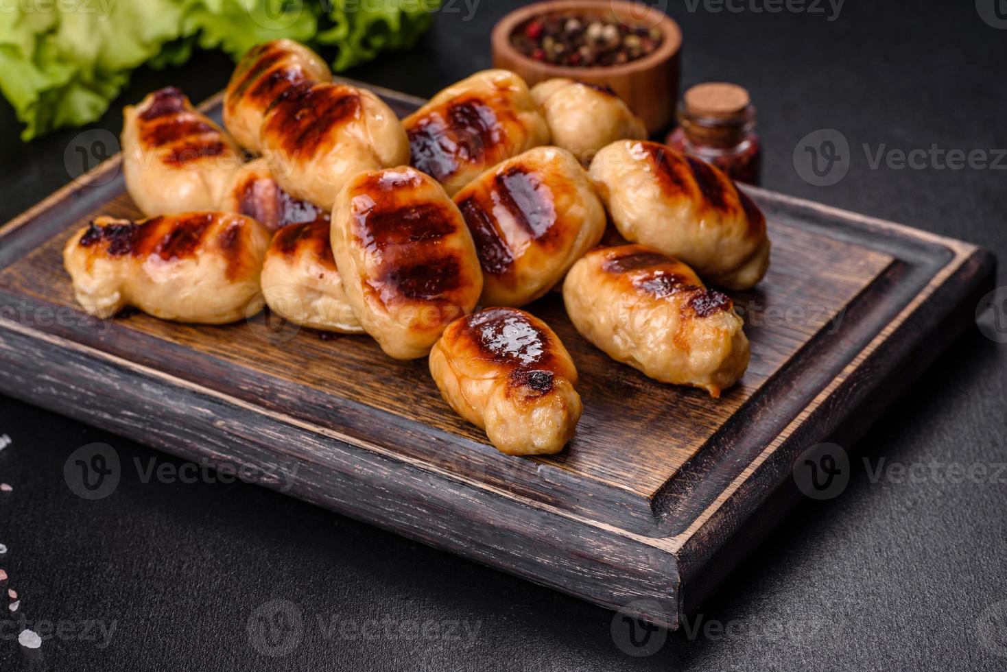 Grilled sausages with spices on a dark stone background photo