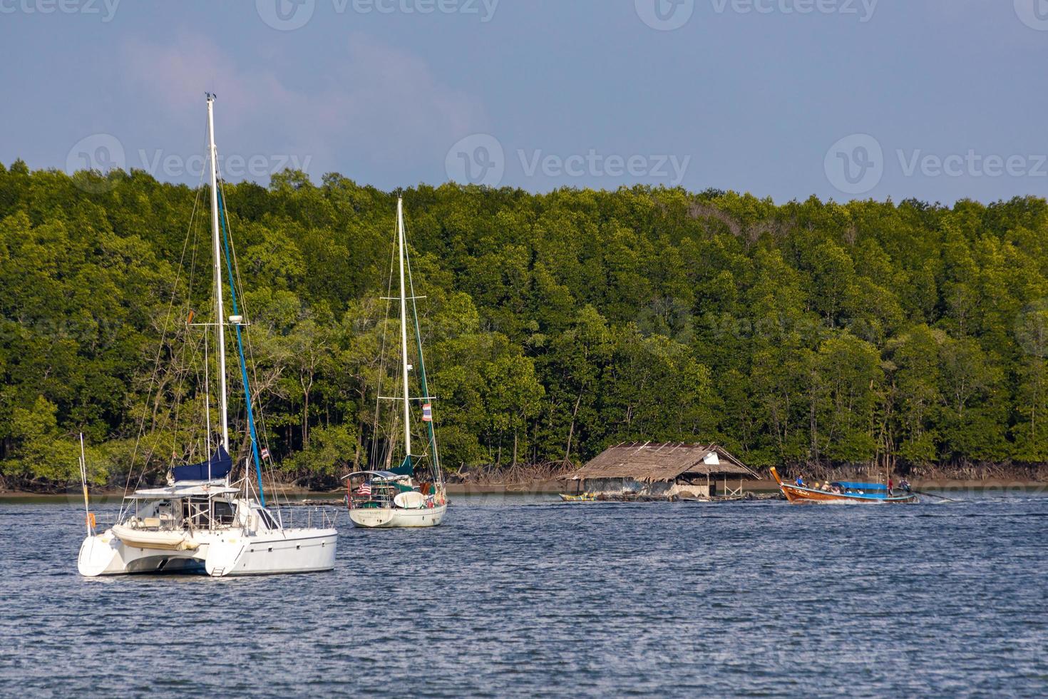 KRABI, THAILAND - JANUARY 22, 2020 - Beautiful natural view of sailboat, boats, pier, mangrove forest and Khao Khanab Nam mountain at Krabi River, Krabi, Thailand. photo