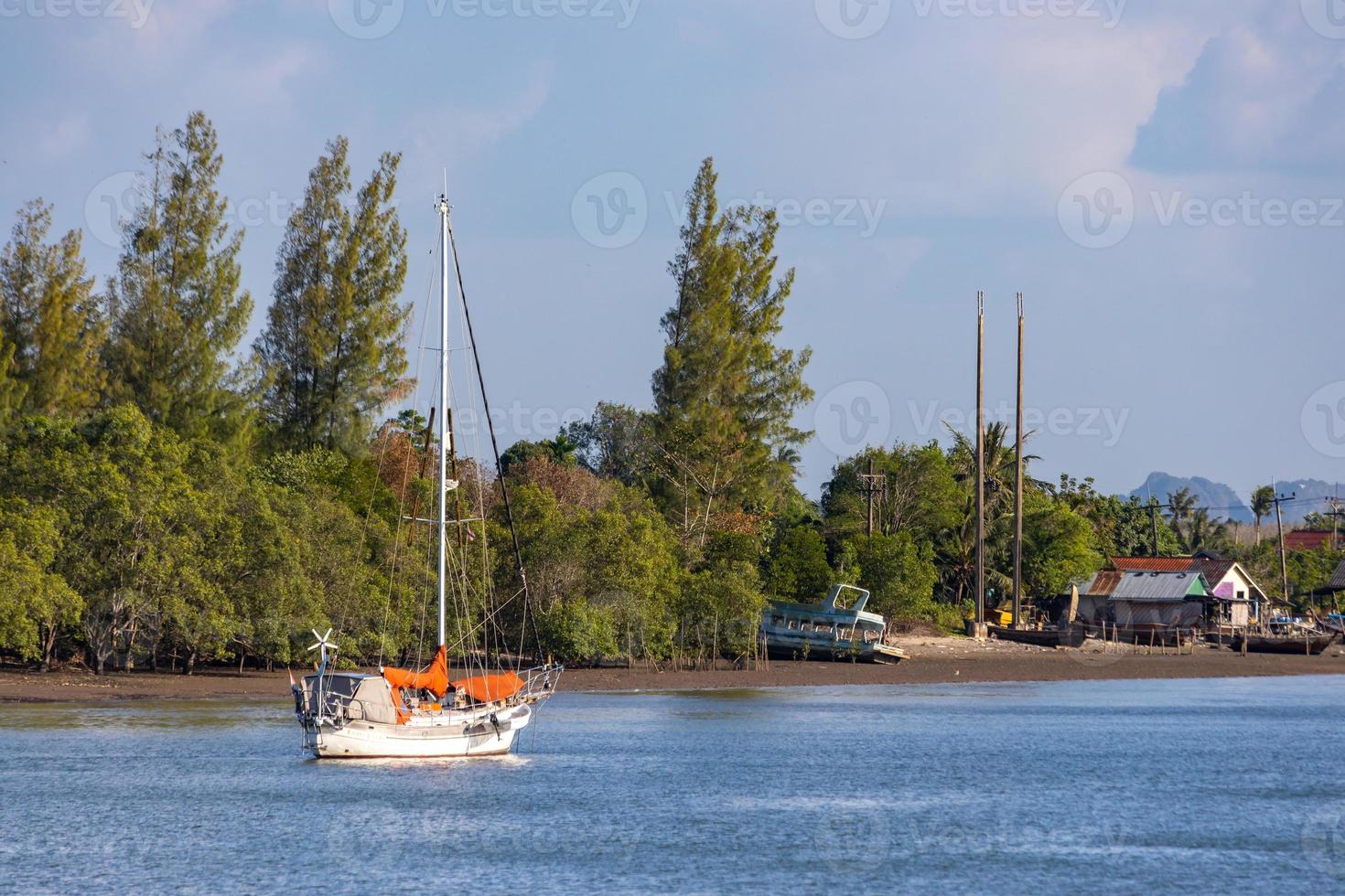 KRABI, THAILAND - JANUARY 22, 2020 - Beautiful natural view of sailboat, boats, pier, mangrove forest and Khao Khanab Nam mountain at Krabi River, Krabi, Thailand. photo