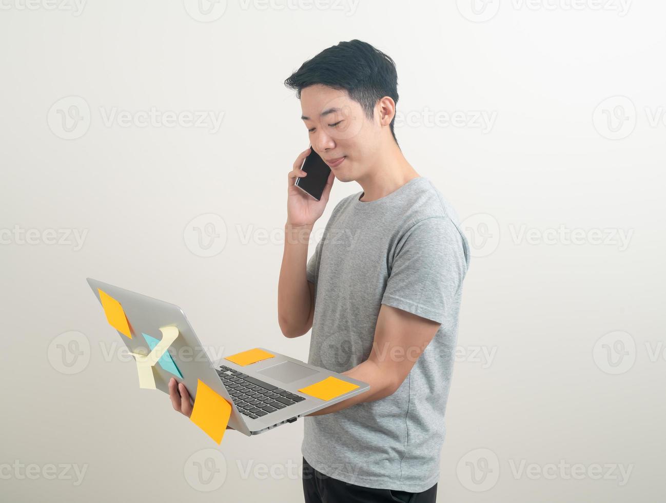 Asian man talking smartphone or mobile phone and hand holding laptop photo