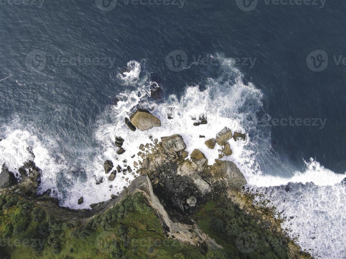 Top down aerial view of giant ocean waves crashing and foaming in coral beach photo