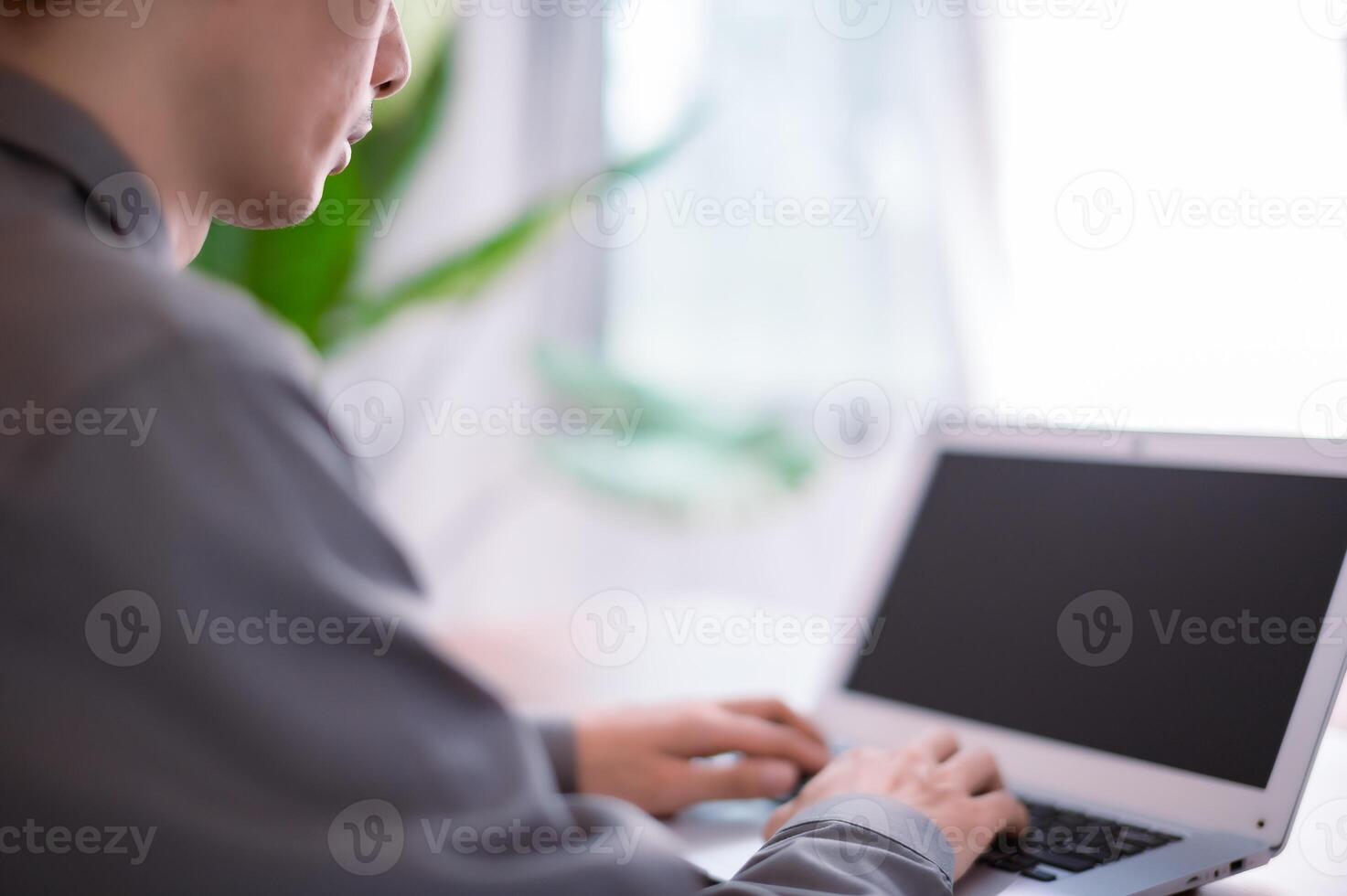 A person sitting at a desk using a laptop computer photo