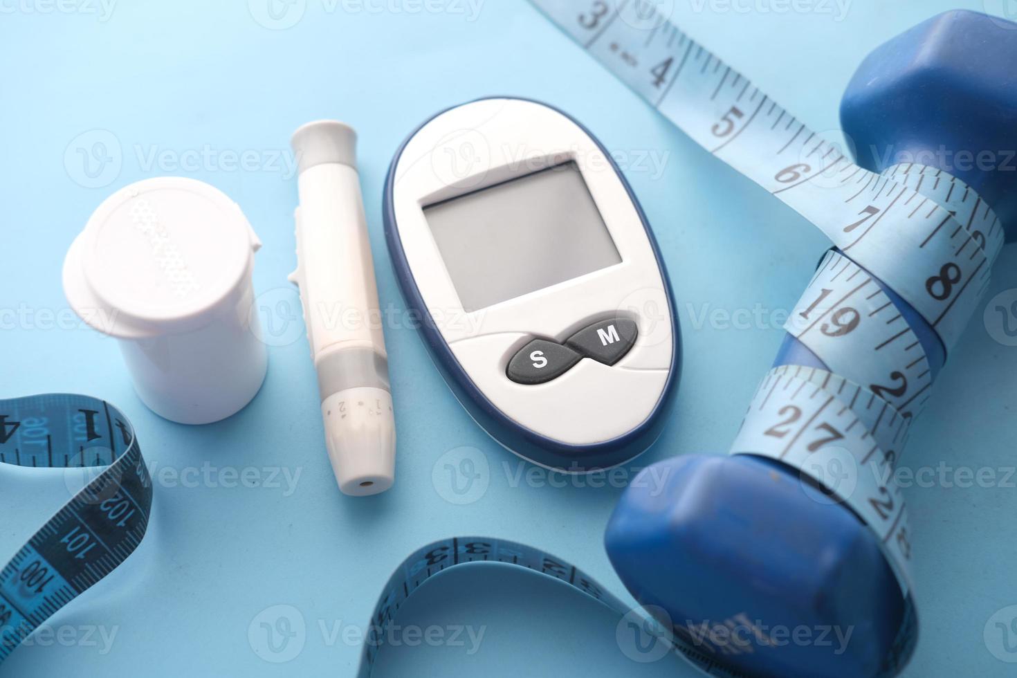 Close up of diabetic measurement tools and dumbbell blue background photo