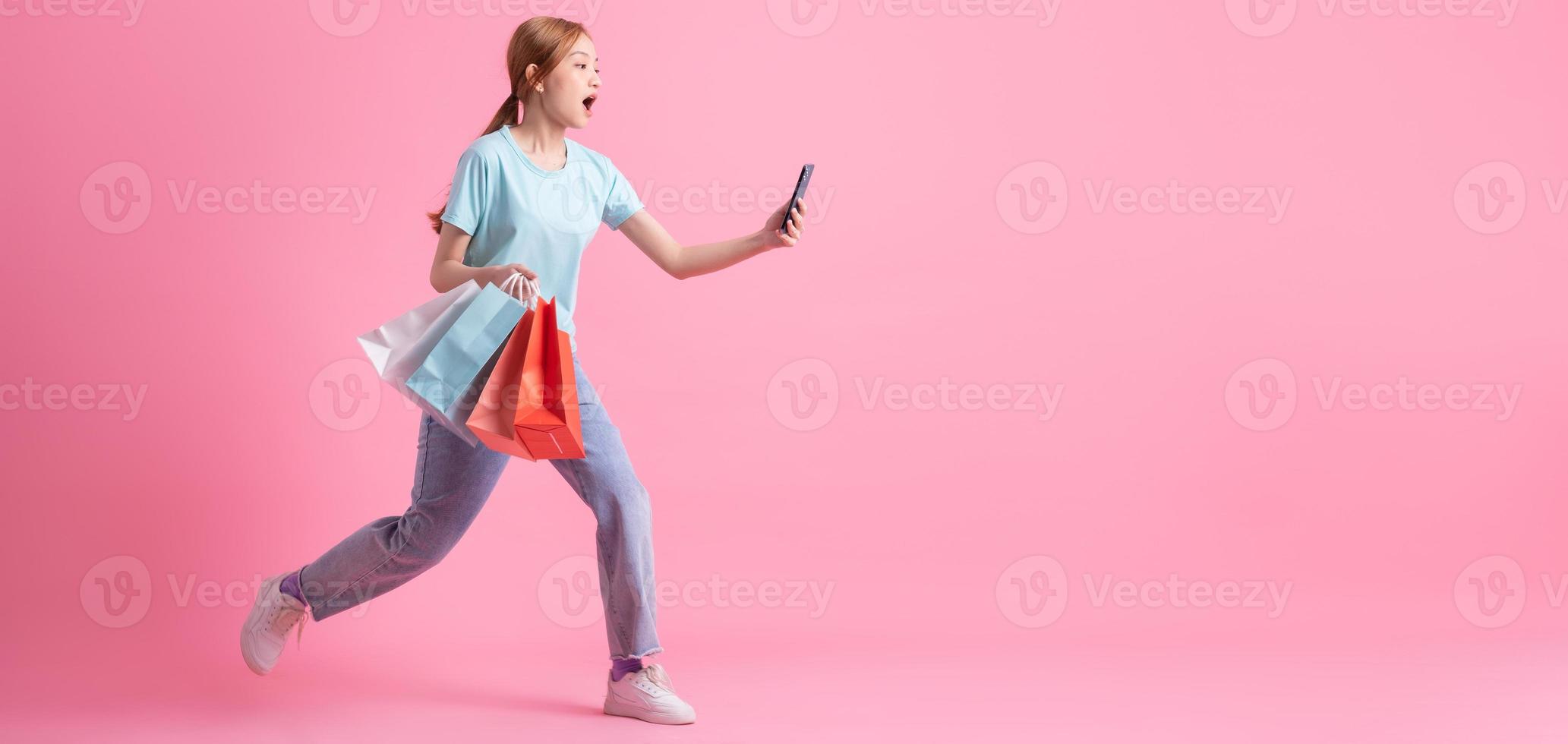 Young Asian woman holding shopping bag on pink background photo