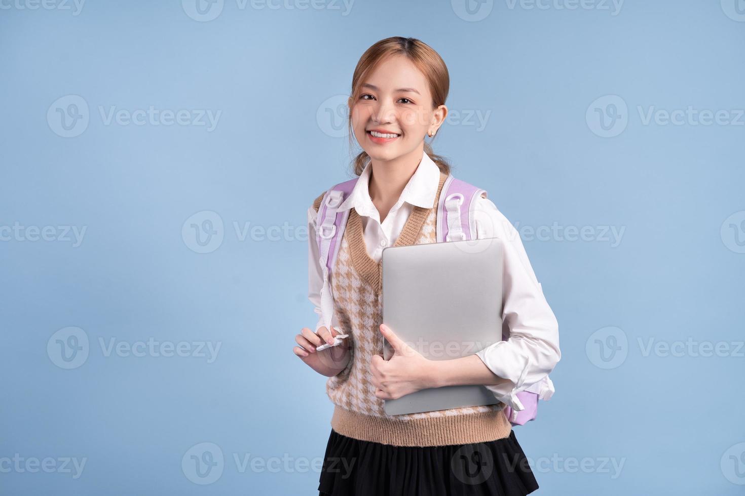 Young Asian high school girl on blue background photo