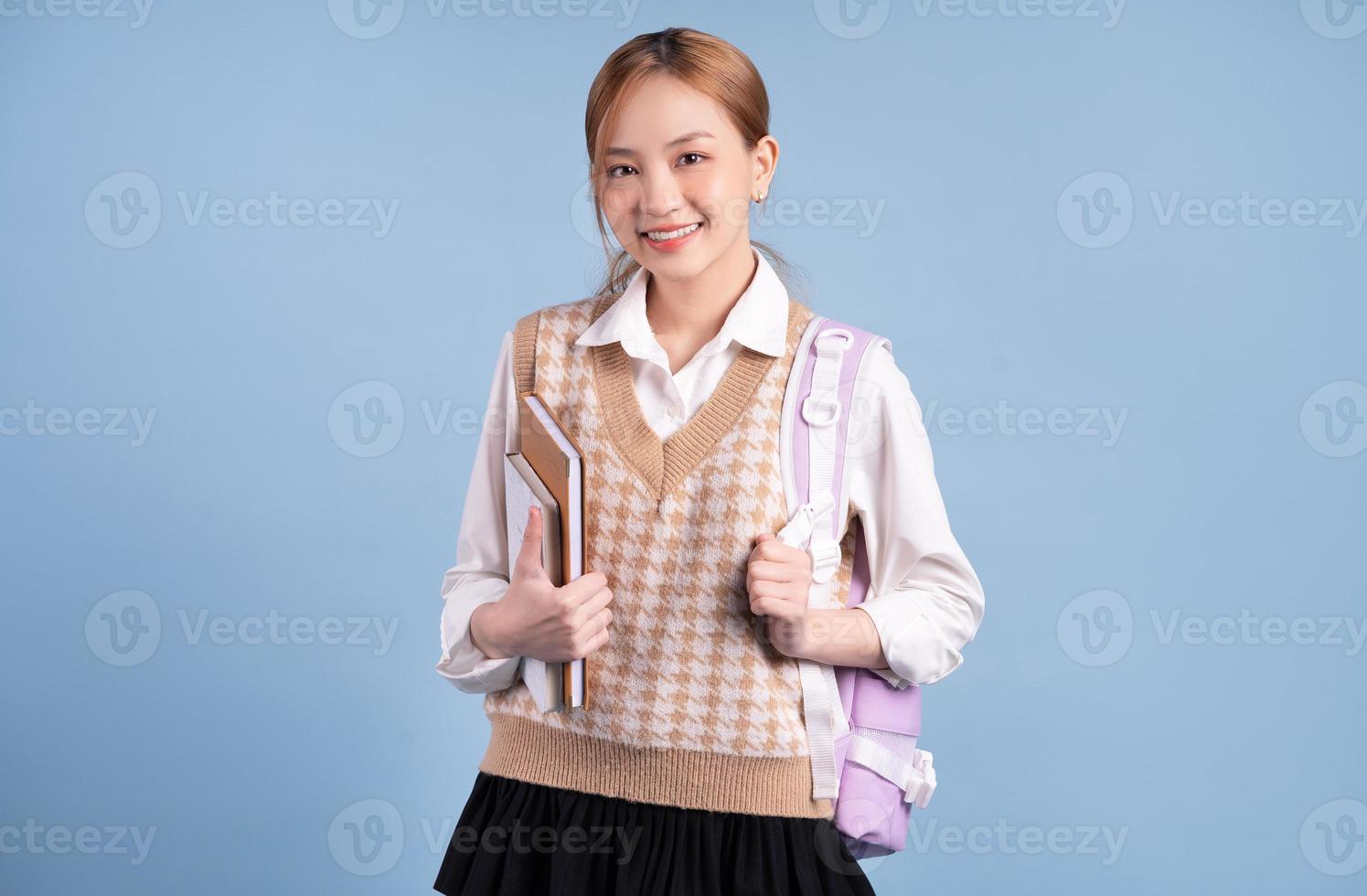 Young Asian high school girl on blue background photo