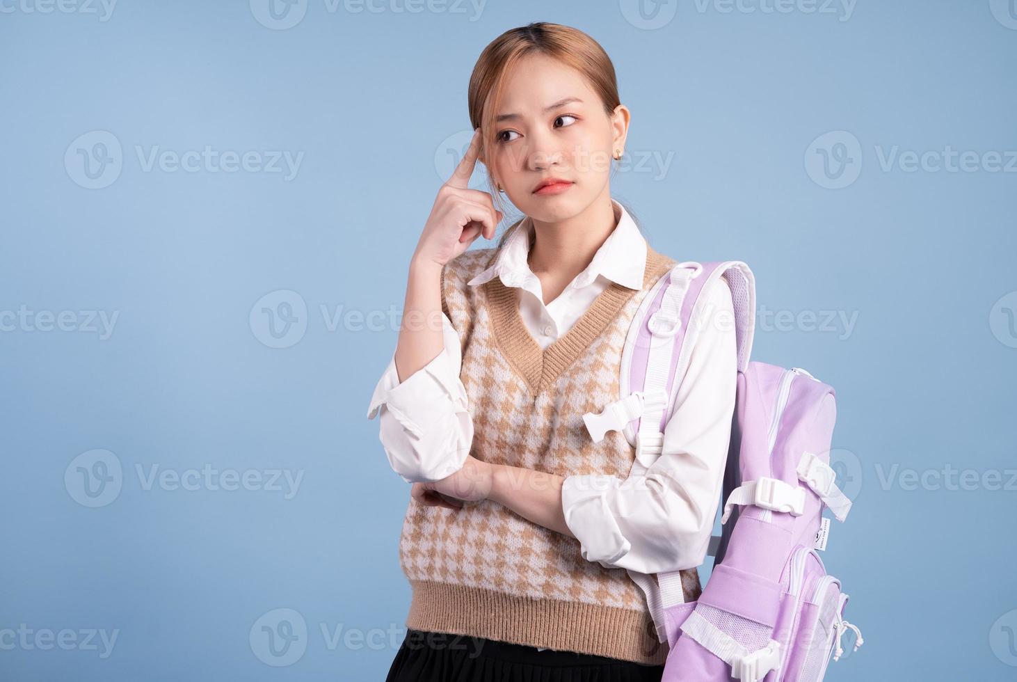 Young Asian high school girl on blue background photo