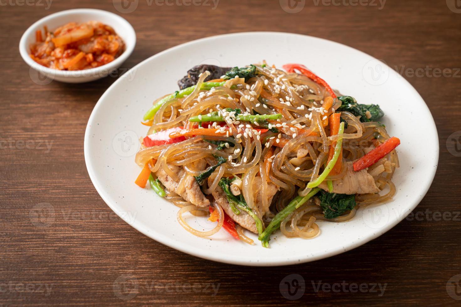 japchae or stir-fried Korean vermicelli noodles with vegetables and pork topped with white sesame photo