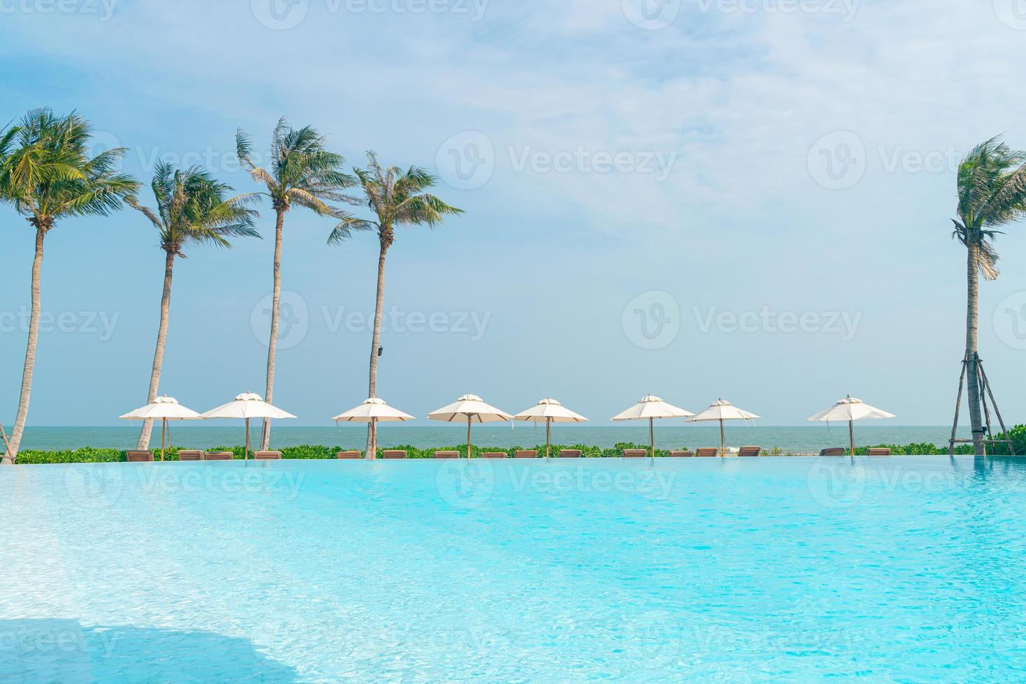 umbrella with bed pool around swimming pool with ocean sea background photo