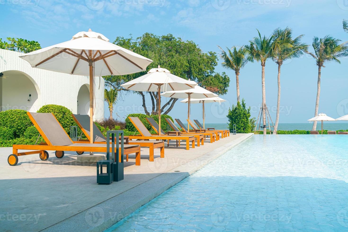 sombrilla con cama piscina alrededor de la piscina con fondo de mar océano foto