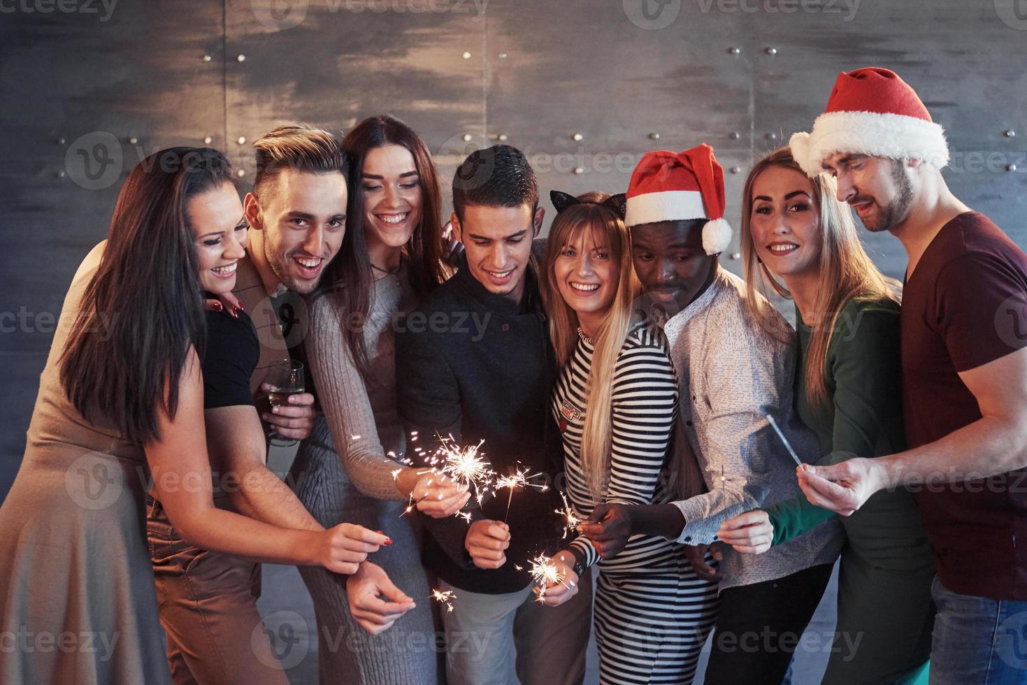 fiesta con amigos. Grupo de jóvenes alegres portando bengalas y copas de champán foto