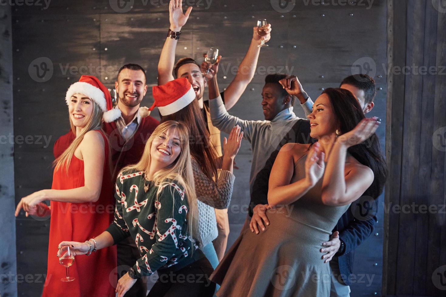 fiesta con amigos. aman la navidad. grupo de jóvenes alegres que llevan bengalas y copas de champán bailando en la fiesta de año nuevo y mirando felices. conceptos sobre el estilo de vida de la unión foto