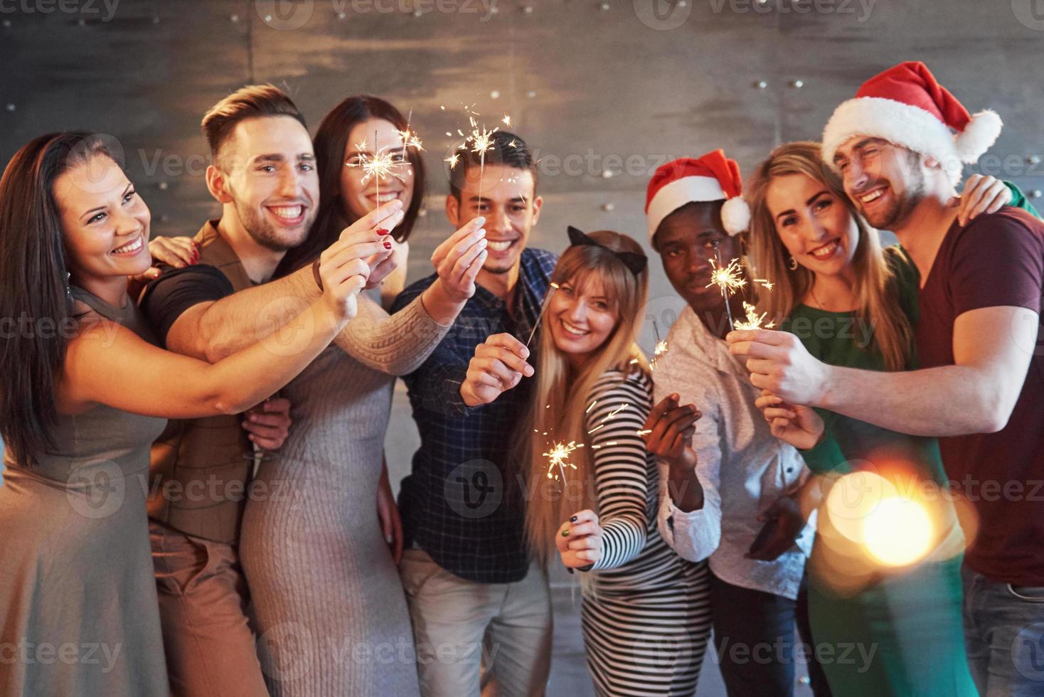 Party with friends. Group of cheerful young people carrying sparklers and champagne flutes photo