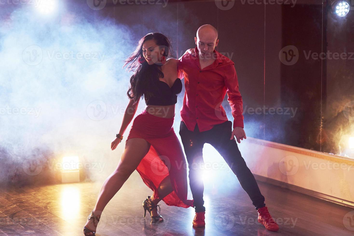 Skillful dancers performing in the dark room under the concert light and smoke. Sensual couple performing an artistic and emotional contemporary dance photo