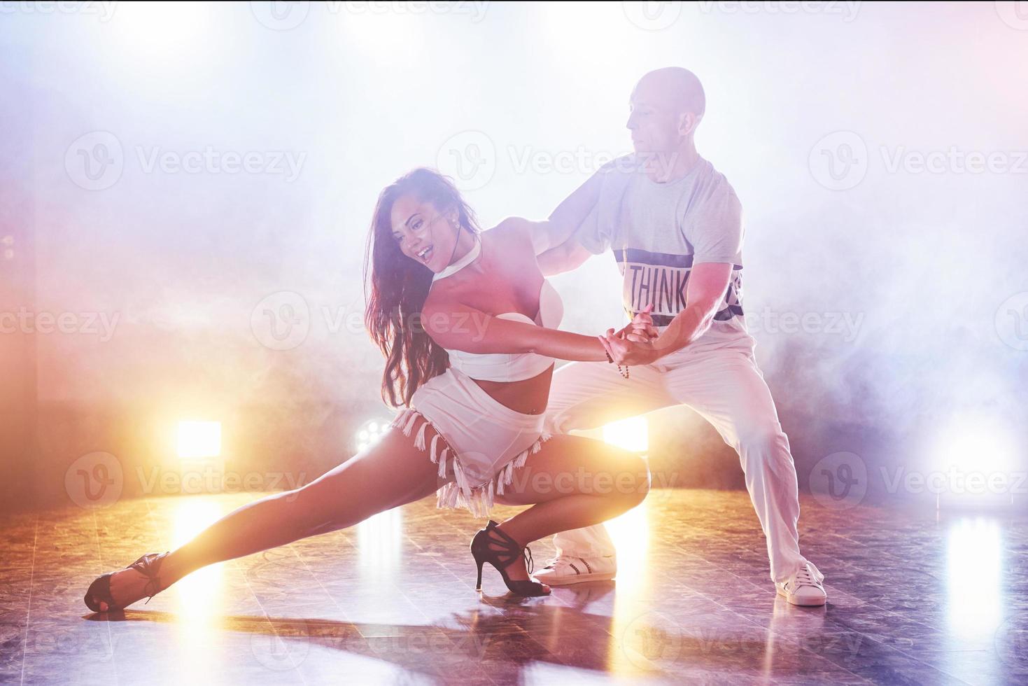 Skillful dancers performing in the dark room under the concert light and smoke. Sensual couple performing an artistic and emotional contemporary dance photo