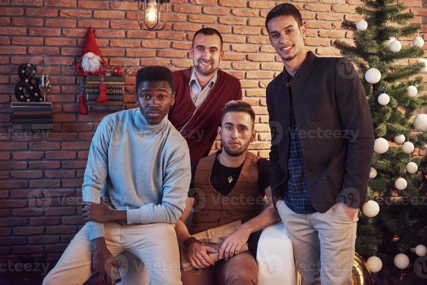 Amigos multiculturales descansando juntos en casa en la víspera de Navidad foto