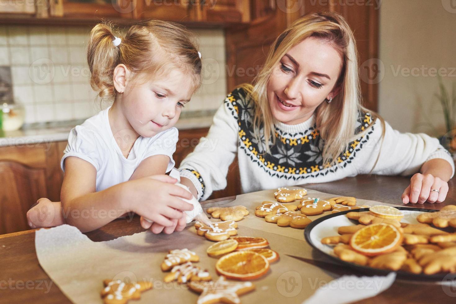 Confectionery workplace with women's hands decorating Christmas cookies. Home bakery, sunny sweet, winter holidays. photo