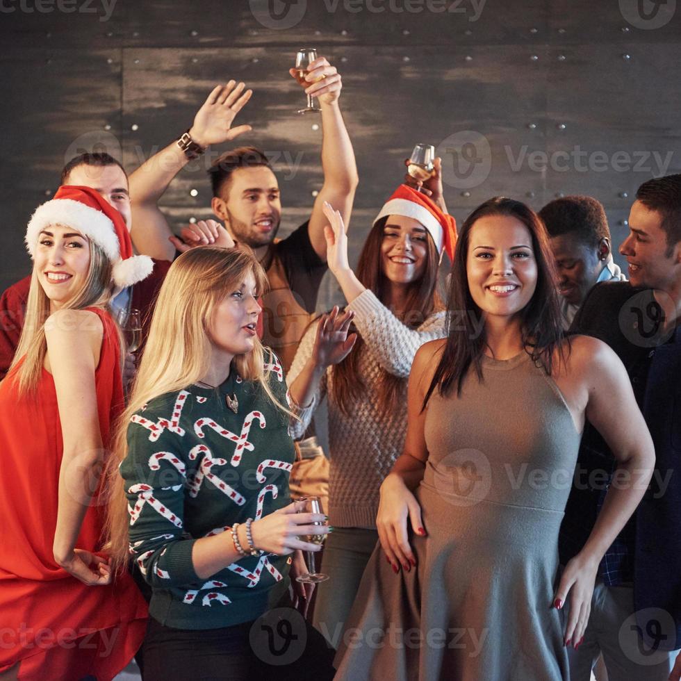 fiesta con amigos. aman la navidad. grupo de jóvenes alegres que llevan bengalas y copas de champán bailando en la fiesta de año nuevo y mirando felices. conceptos sobre el estilo de vida de la unión foto