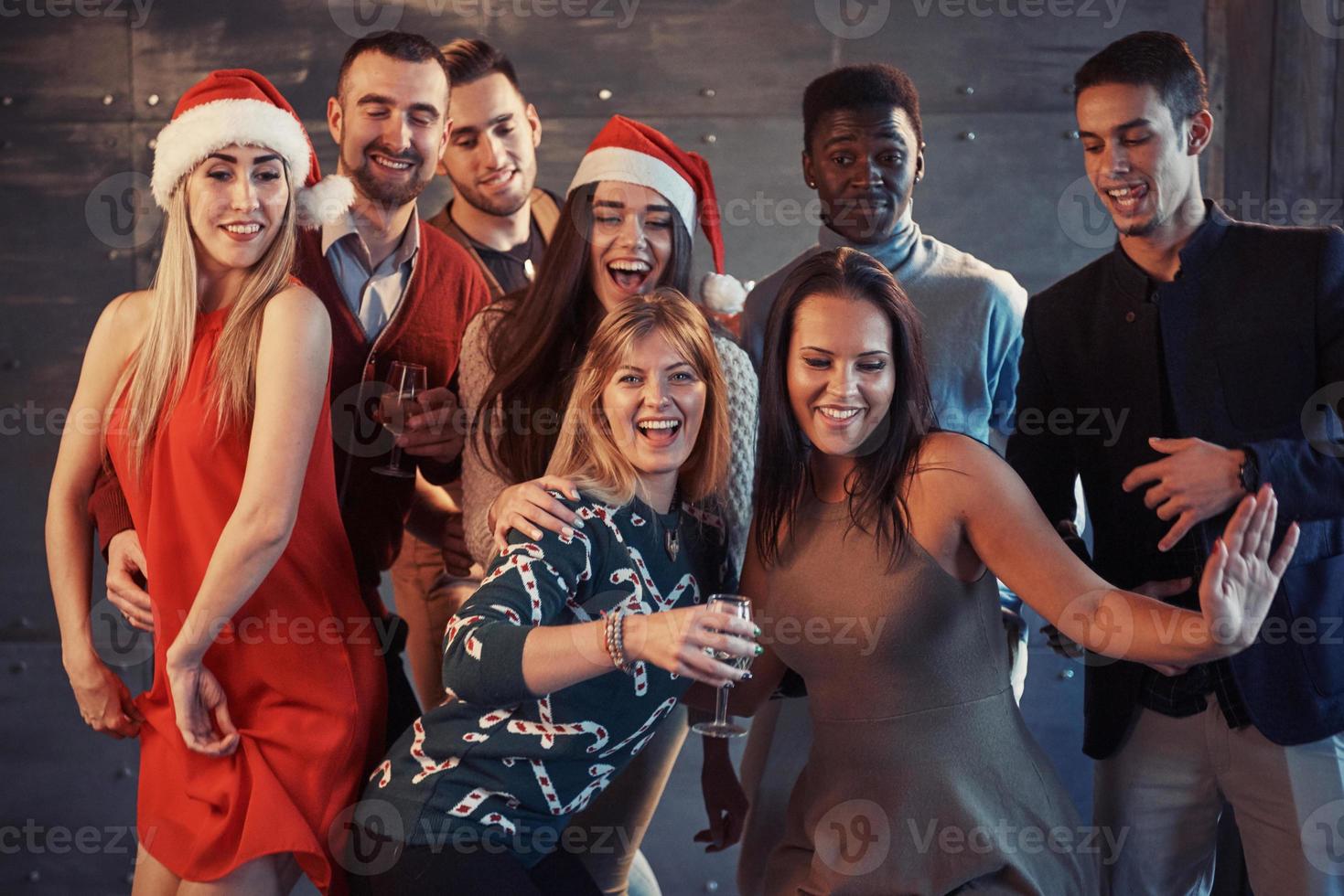 fiesta con amigos. aman la navidad. grupo de jóvenes alegres que llevan bengalas y copas de champán bailando en la fiesta de año nuevo y mirando felices. conceptos sobre el estilo de vida de la unión foto