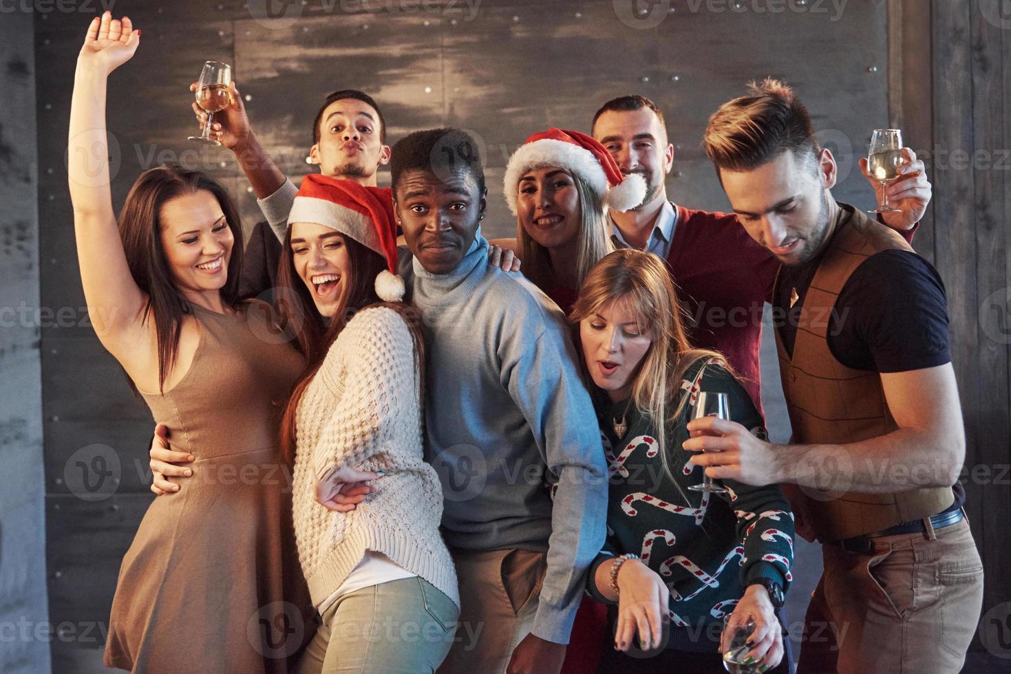 fiesta con amigos. aman la navidad. grupo de jóvenes alegres que llevan bengalas y copas de champán bailando en la fiesta de año nuevo y mirando felices. conceptos sobre el estilo de vida de la unión foto