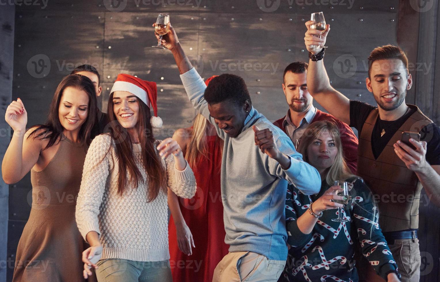 Party with friends. They love Christmas. Group of cheerful young people carrying sparklers and champagne flutes dancing in new year party and looking happy. Concepts about togetherness lifestyle photo