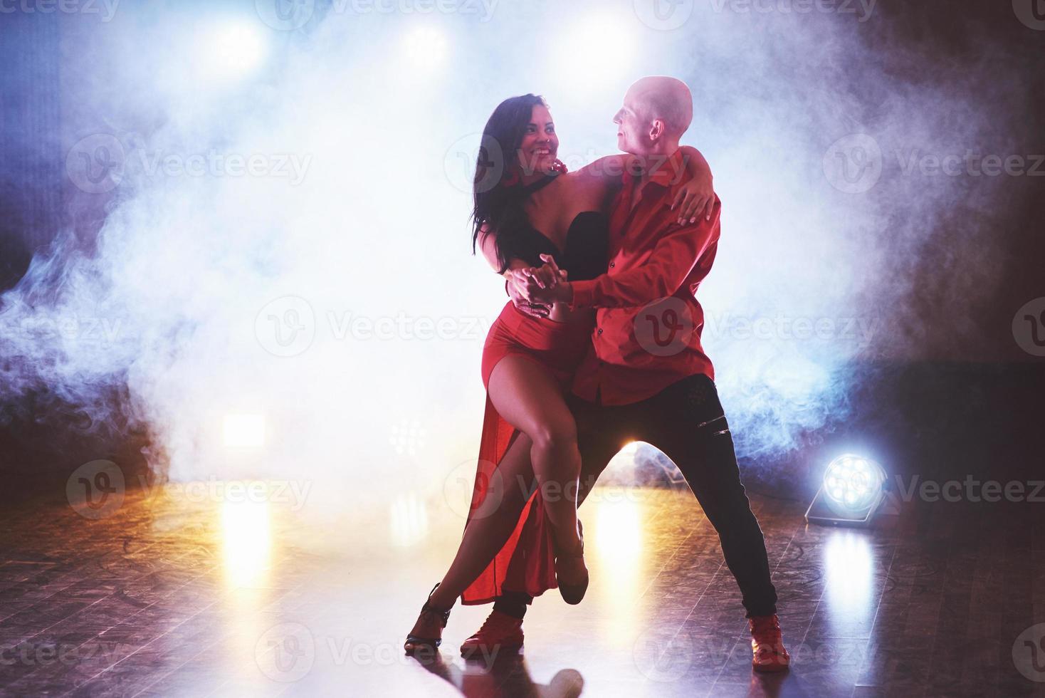 Skillful dancers performing in the dark room under the concert light and smoke. Sensual couple performing an artistic and emotional contemporary dance photo