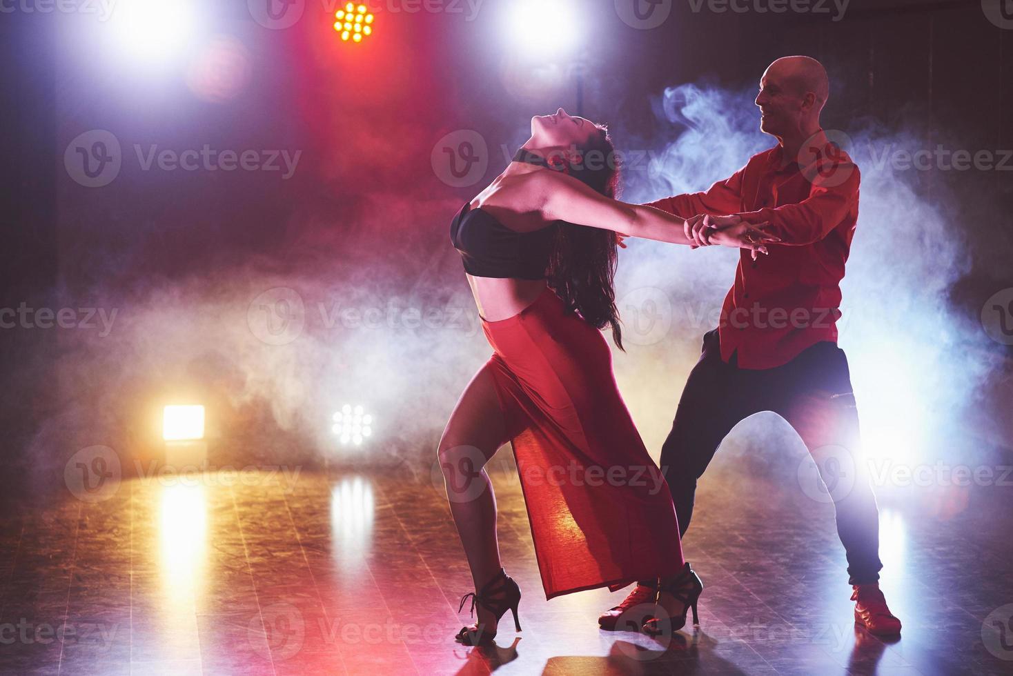 Skillful dancers performing in the dark room under the concert light and smoke. Sensual couple performing an artistic and emotional contemporary dance photo