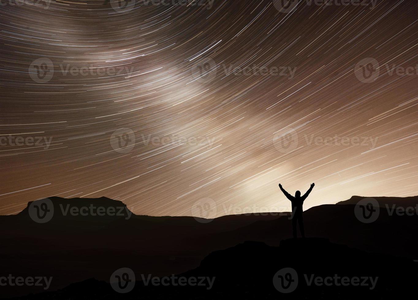 silueta de una aventura de fotógrafo feliz caminando por la montaña con estrellas en movimiento de fantasía real en el cielo nocturno. conceptual de naturaleza asombrosa con gran viaje de ensueño y escena de viaje foto