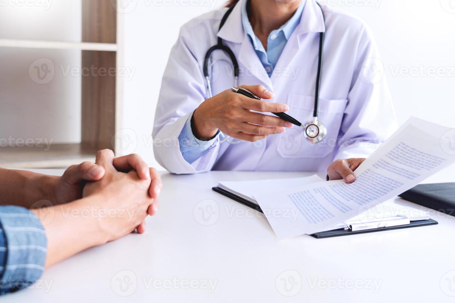 el paciente escucha atentamente a un médico que explica los síntomas del paciente o hace una pregunta mientras discuten el papeleo juntos en una consulta foto