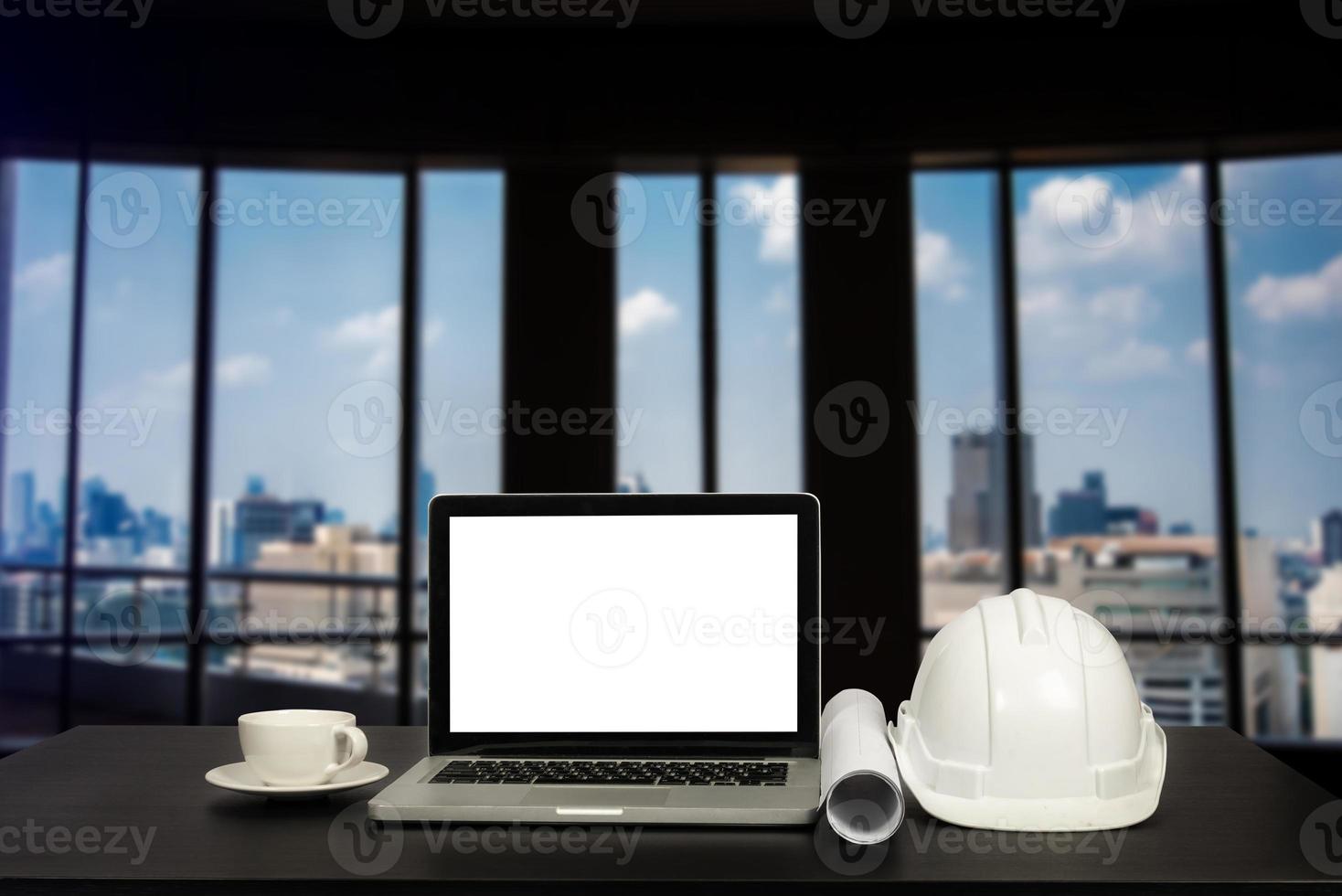 Laptop computer and office construction on table in office blurred background.Architect concept. photo