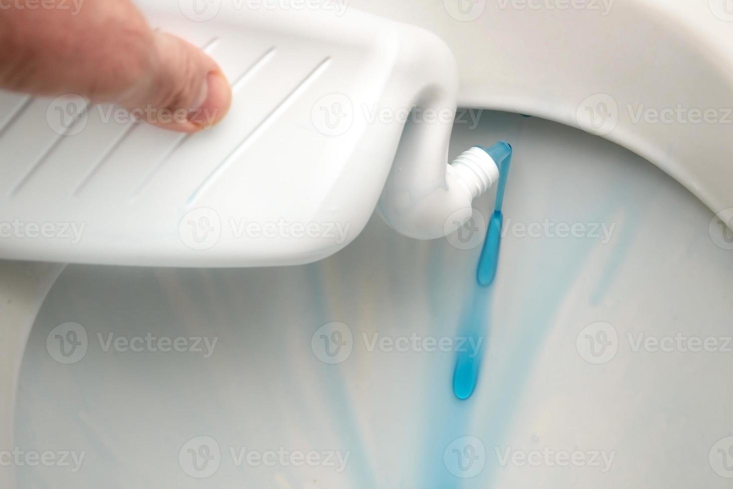 mano masculina aplicando detergente líquido en un inodoro de una botella especial para limpiar el inodoro de cerca foto