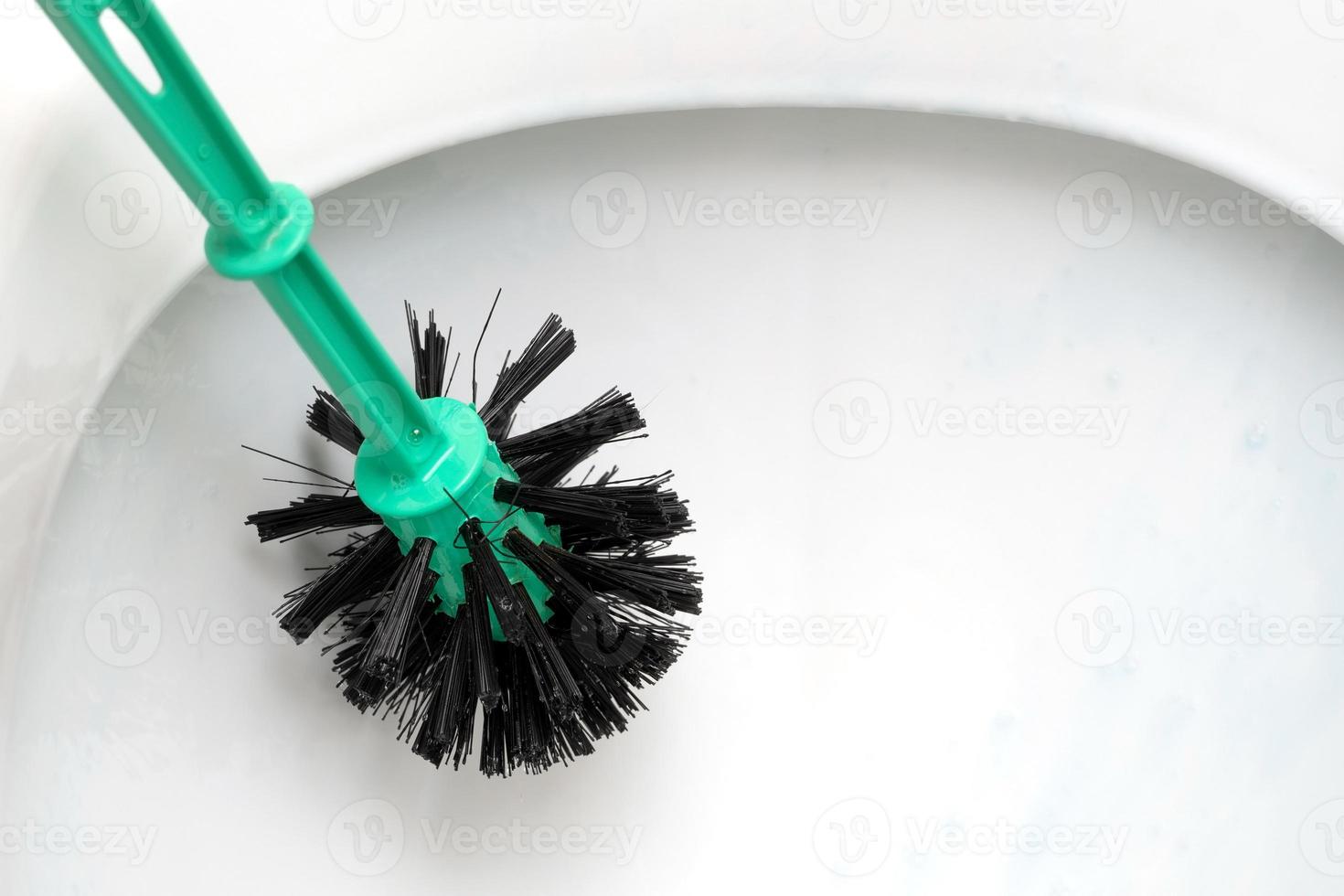 Cleaning a toilet bowl using a toilet brush close up photo