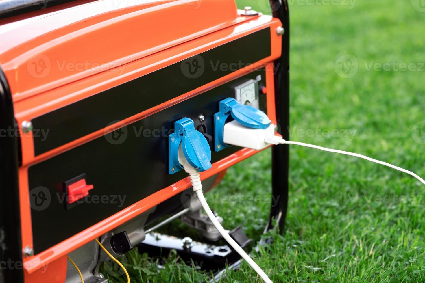 Electric wires connected to a portable generator on the green grass in summer outdoors close up photo