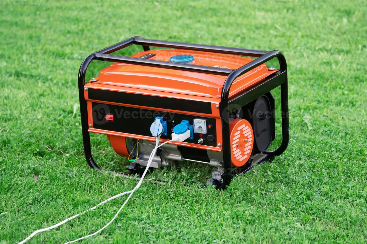 Portable electric generator with electric wires connected on the green grass in summer photo