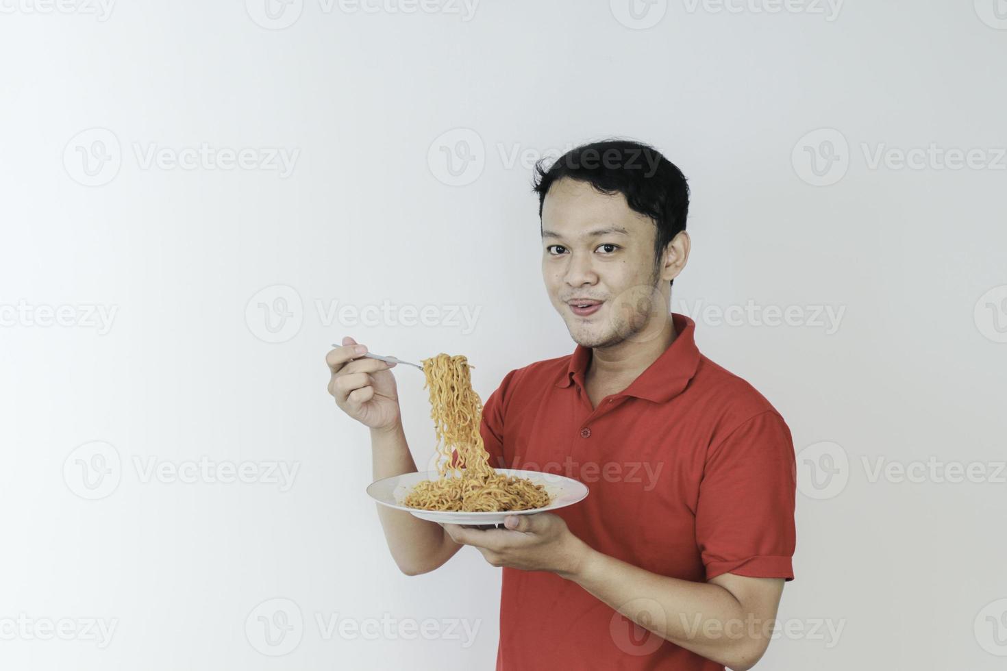 Portrait of happy Young Asian man enjoys noodles with tongue out. Eating lunch concept. photo