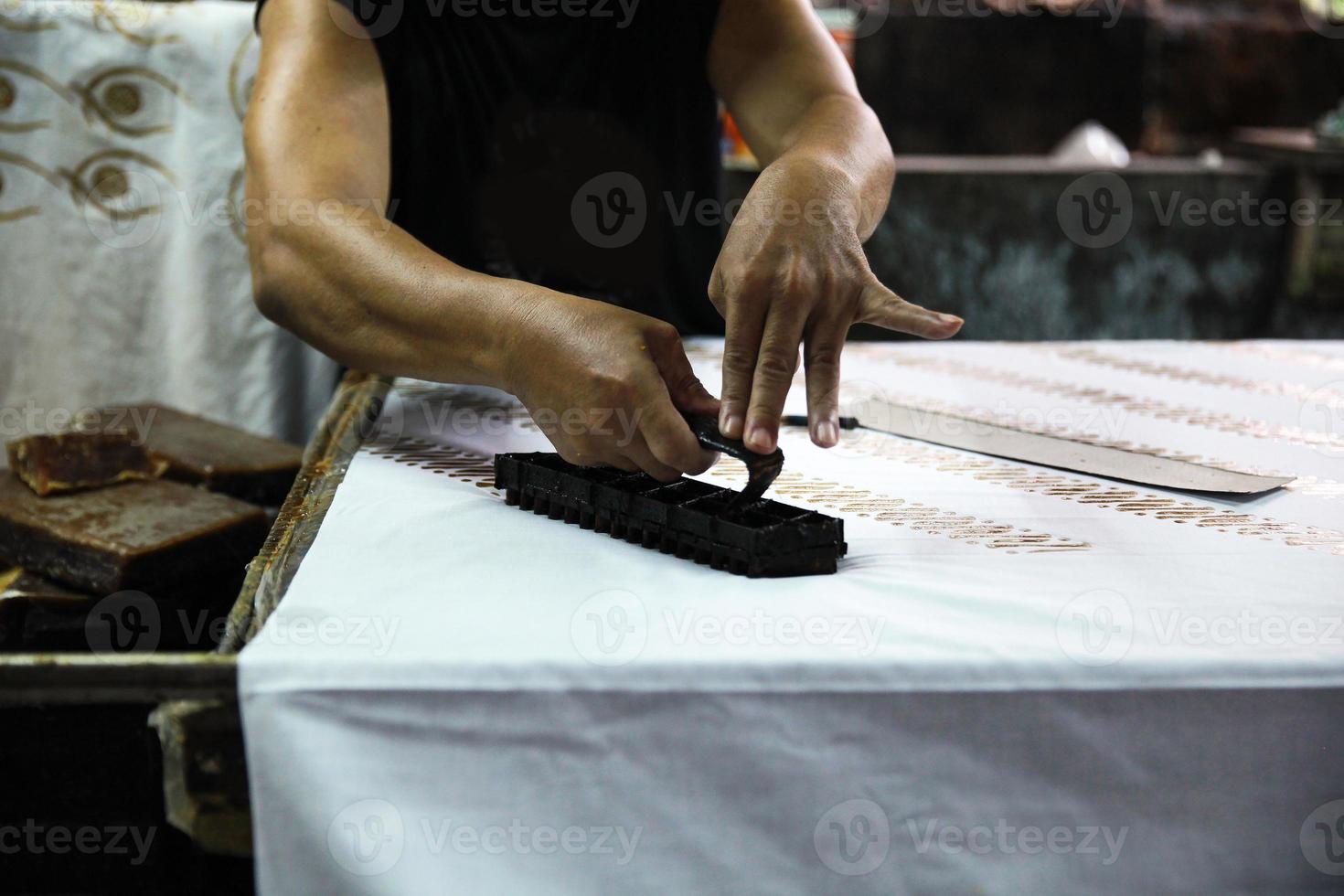 Hand of craftsmen making Indonesian traditional fabric called kain batik photo