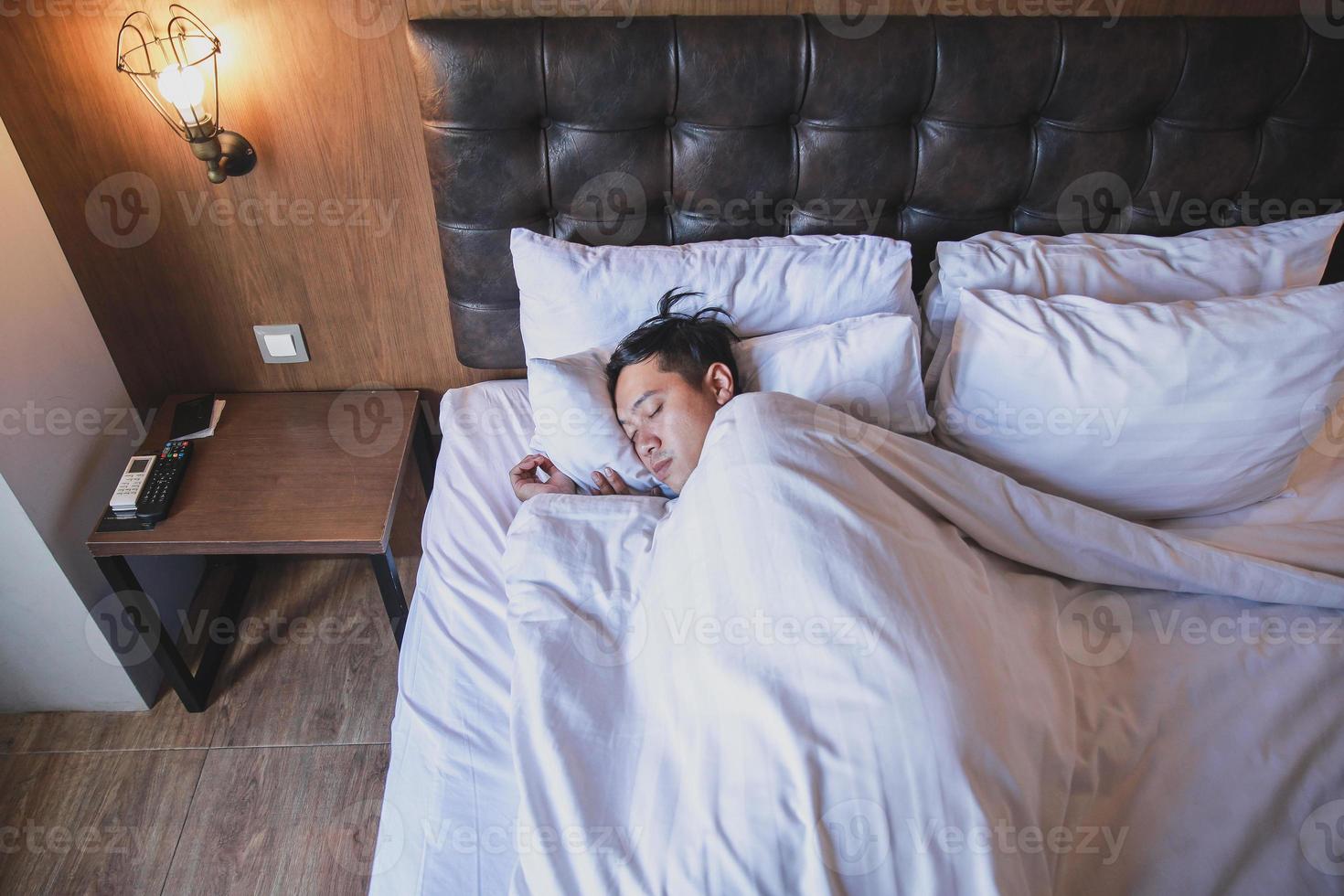 Asian man sleeping tightly on white bed photo
