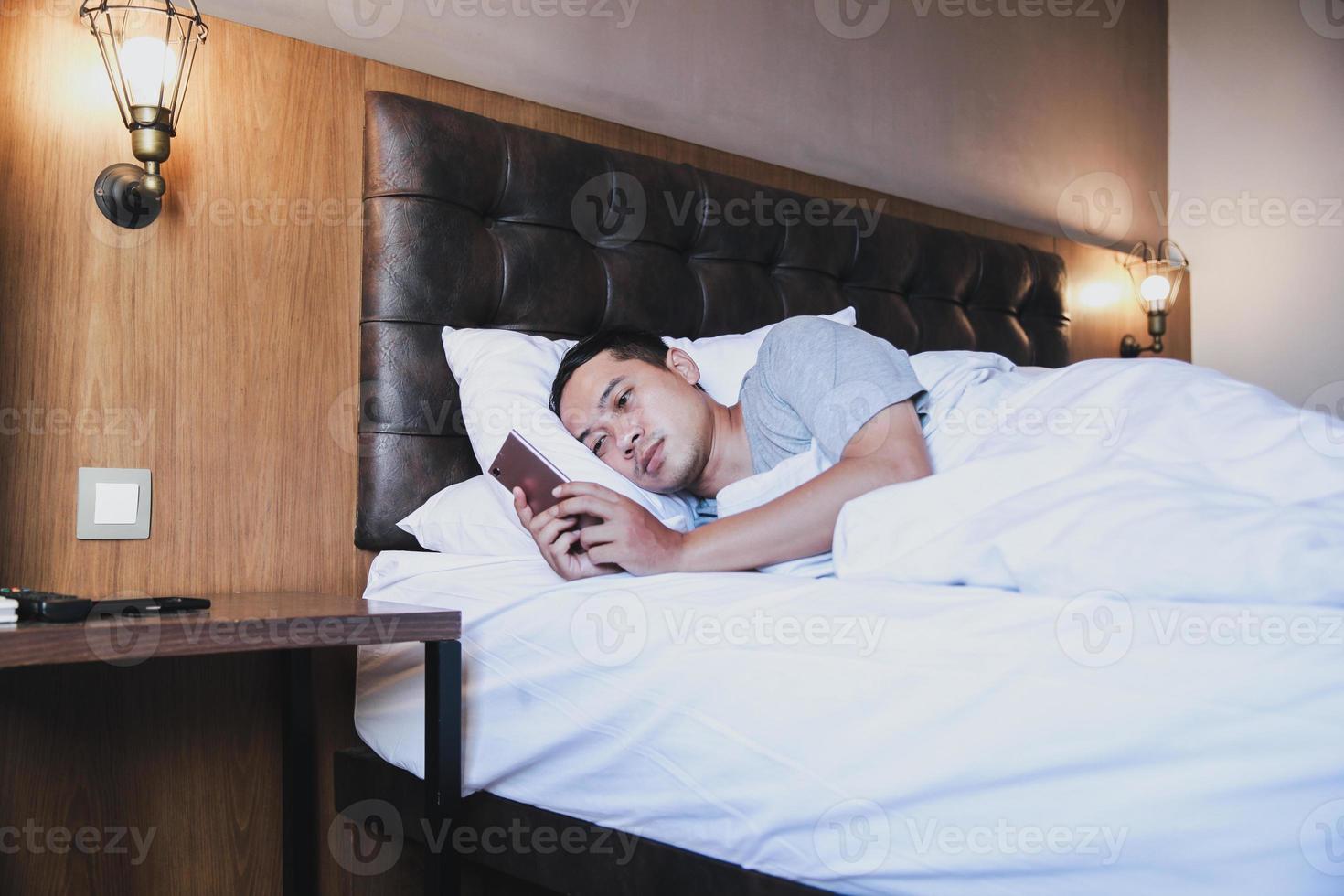 Insomnia men using smartphone  on the bed while lying under the blanket photo