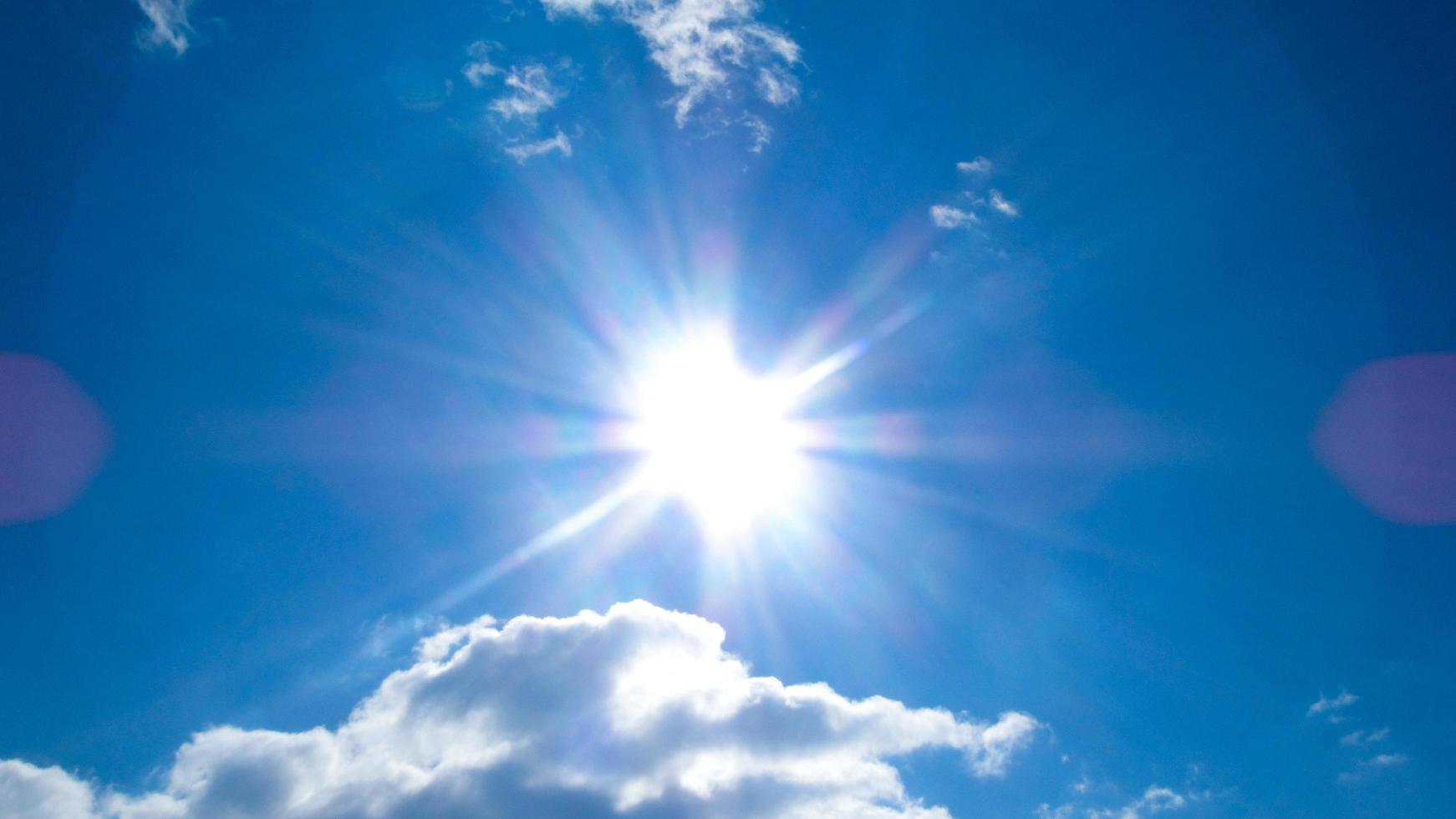 sun on the background of a blue sky with white clouds photo