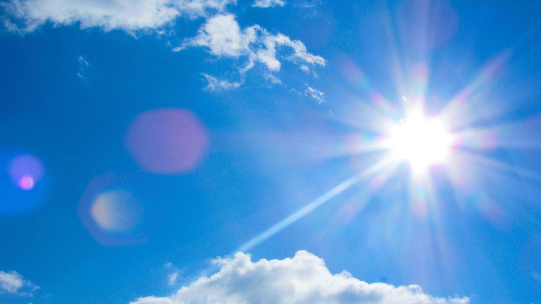 sun on the background of a blue sky with white clouds photo