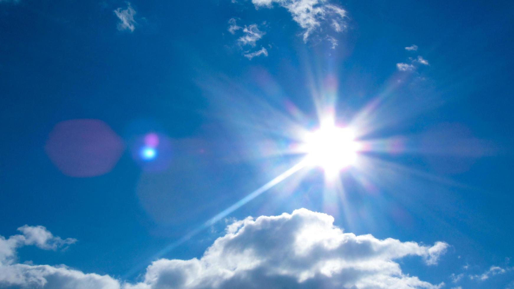 sun on the background of a blue sky with white clouds photo