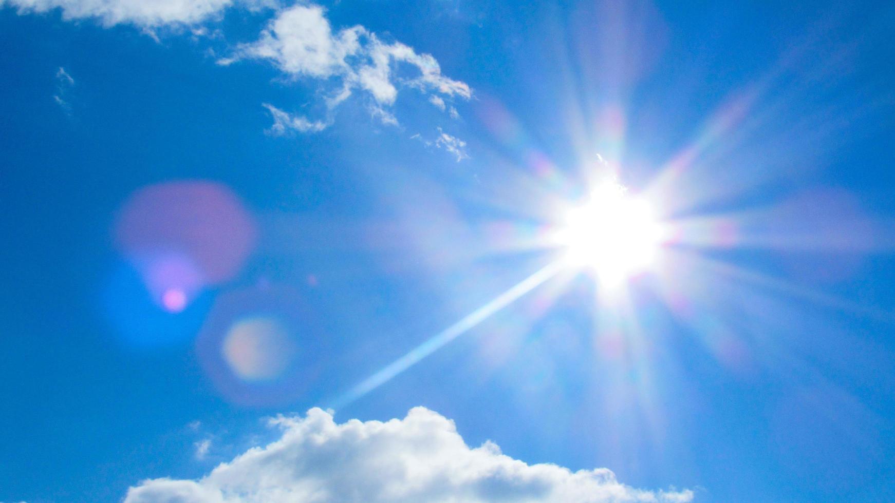 sun on the background of a blue sky with white clouds photo