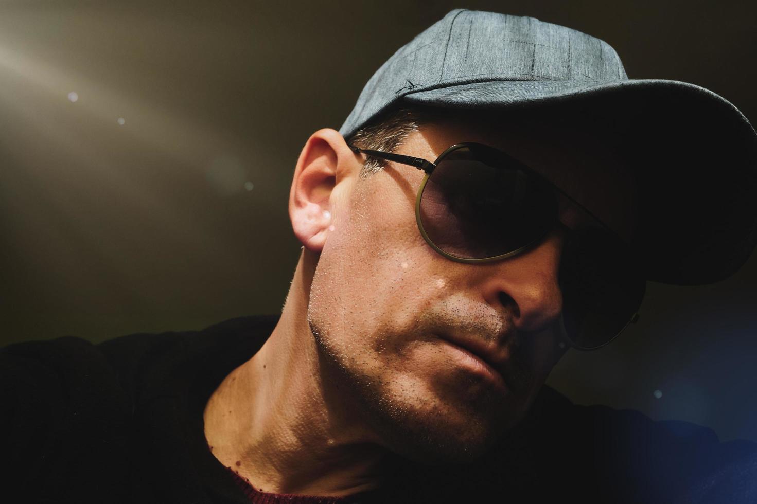 man wiht cap and sunglasses taking a selfie in the shadows photo