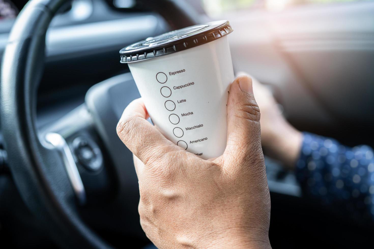 Asian lady holding hot coffee cup food for drink in car, dangerous and risk an accident. photo